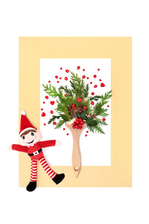 Christmas Eve art fun with santa elf, paintbrush, red hearts, holly berries, winter greenery on white with gold frame. Festive love surreal design for greeting card, gift tag.の写真素材