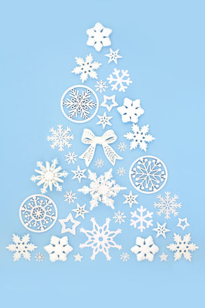 Surreal Christmas tree shape with white snowflake and bauble decorations on blue background. Festive fun abstract winter magic design for Xmas, Yule Noel.の写真素材