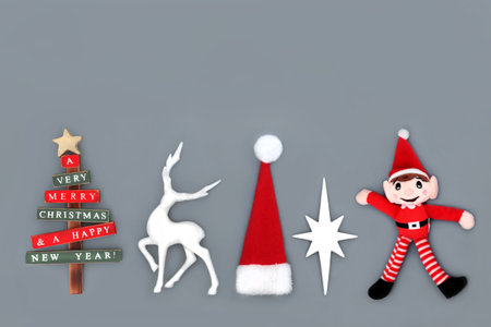 Symbols of Christmas Eve for the holiday season background on gray. Tree, reindeer, santa hat, star, elf festive bauble decorations.の写真素材