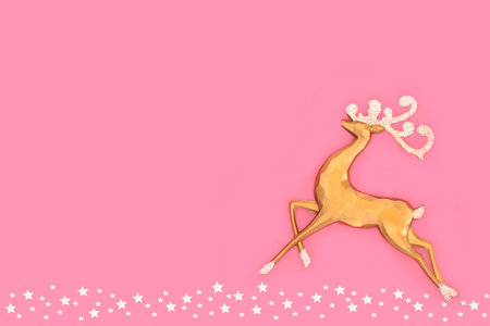 Christmas gold reindeer santa helper on pink background with star decorations. Magical fantasy tree decoration for holiday season. Greeting card, gift tag, invitation.の写真素材