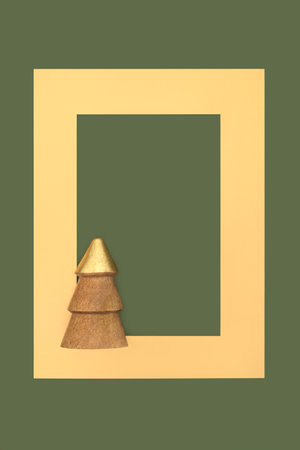 Wooden gold Christmas tree decoration on bottle green background with frame. Festive minimal eco friendly abstract design for Yule, Noel, Xmas holiday season. Copy space.の写真素材