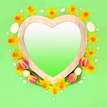 Heart frame with easter eggs and yellow spring tulip and narcissus flowers on green background with gradient fill. Seasonal romantic floral nature symbol.の写真素材