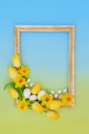 Easter eggs and spring flowers gold frame background design. Seasonal symbols, edible sweet food candy design for holiday season on gradient blue yellow.の写真素材