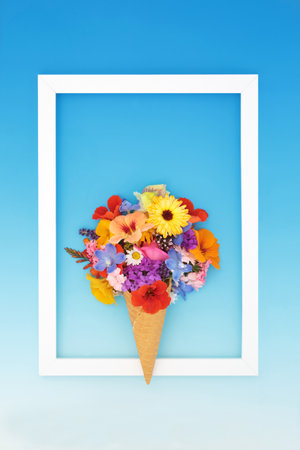 Surreal ice cream cornet with vivid summer flowers on gradient blue background with white frame. Fun abstract floral quirky design.の写真素材