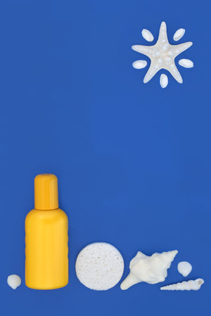 Summer suntan lotion bottle, soap and sponge, seashell, abstract starfish sun on blue. Holiday skin protection, sunblock body care moisturizing cream.の写真素材