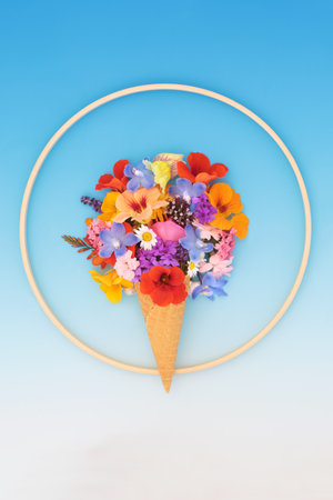 Surreal ice cream with fresh summer flowers on gradient blue white background with wooden frame. Fun abstract floral whimsical design for greeting card.の写真素材