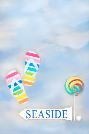 Seaside arrow sign with summer rainbow flip flops, rock candy lollipop on sky background. Holiday vacation travel leisure symbols and fun conceptの写真素材