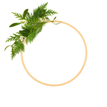 Winter flora wreath decoration with cedar fir, mistletoe ivy greenery wooden frame on white background. Abstract minimal garland design for solstice.の写真素材