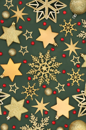 Christmas gold tree decorations, holly red berries, star, snowflake and sphere ball shape baubles. Background festive symbols theme on green.の写真素材