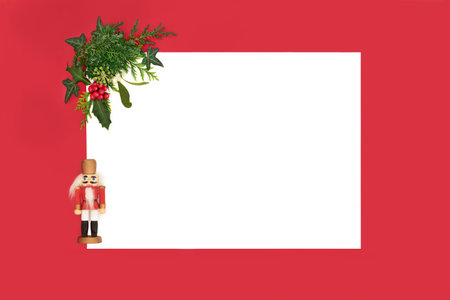 Nutcracker toy soldier decoration with winter flora holly berries, mistletoe, ivy, fir on white red...