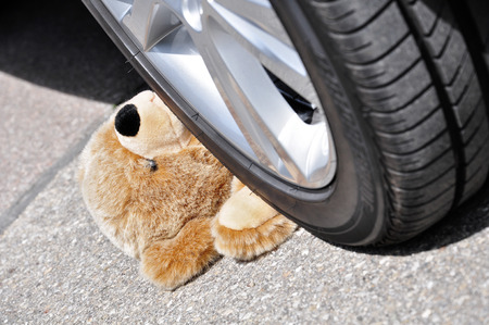 Teddy under car tires, symbolic car accident with playing childrenの写真素材