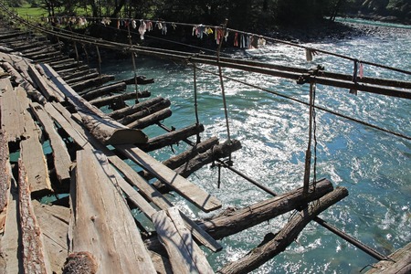 Long pedestrian suspension bridge over the mountain river Bzyb on a sunny autumn day in Abkhazia. Georgia.の写真素材