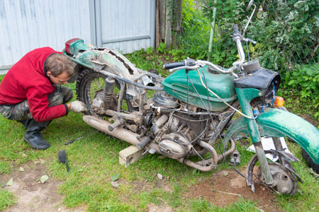 Repairs of an old motorcycle "Ural" in the summer in warm weather in the countryのeditorial素材