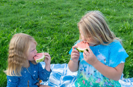 Children enjoy eating delicious, red, ripe, juicy, appetizing watermelonの写真素材