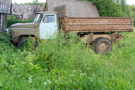 Old truck in the village on a green meadow in summer.
