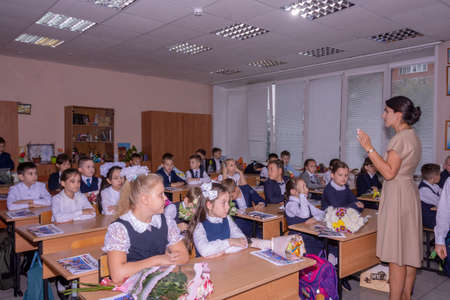 Knowledge Day. September 1. Beautiful and elegant elementary school students are sitting at their desks in the classroom.のeditorial素材