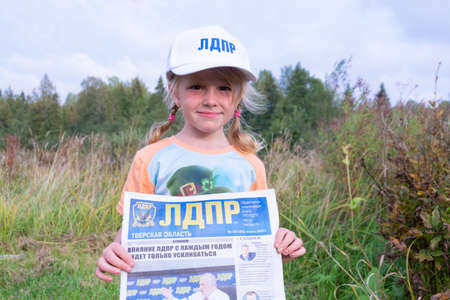 A girl in a white cap with the inscription "LDPR" holds the newspaper LDPR Tver region.のeditorial素材