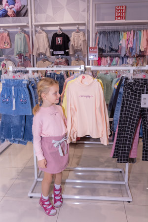 A girl chooses children's clothes in a store. 4DAILY shopping CENTER.のeditorial素材