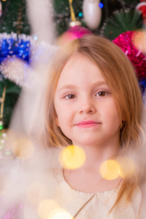 A beautiful elegant girl near the Christmas tree in the New Year.の写真素材
