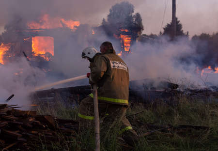 Fire service employees extinguish the fire. Firefighters at the scene of the fire. A fire in the village. Burning wooden houses in the village of Rantsevo, Tver region.のeditorial素材