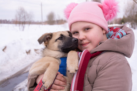 On a frosty winter day, a girl walks down the street with a beautiful little puppy.