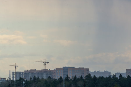 Construction site with cranes and buildings on a background of blue skyの写真素材