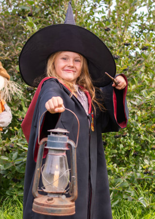 Little girl in a witch costume with a lantern in her hands. Halloween. A girl in a robe and hat. A little sorceress in the costumeの写真素材