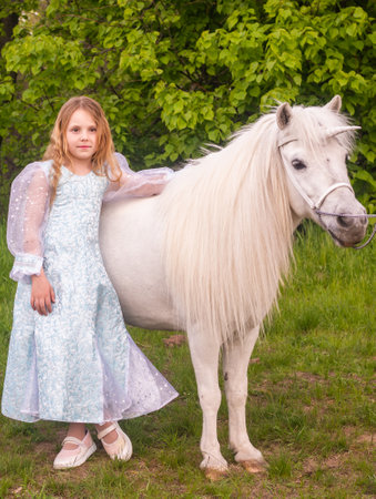 Portrait. A beautiful elegant girl with a magical fairy unicorn. A girl and a white pony. The child is a model.の写真素材