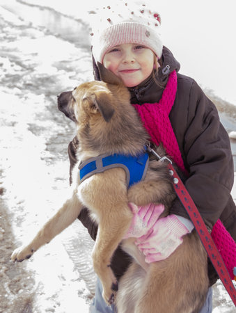 Little girl with her dog on a walk in the park in winterの写真素材