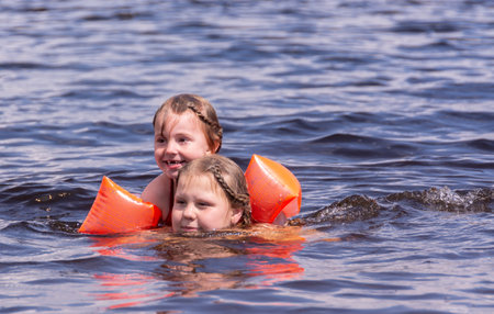 On a hot summer day, children relax on the lake. Girls on the beach. People frolic in the water.