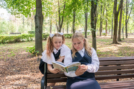 Knowledge day. The first of September. Beautiful elegant girls with fashionable hairstyle in school uniform in the park. Schoolgirl. Schoolgirl. September 2024.の写真素材