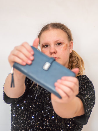 A beautiful model girl in a fashionable black dress holds a leather purse in her hands. Portrait.