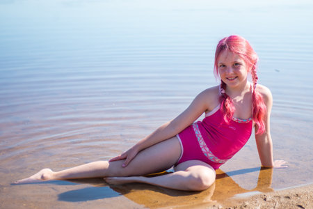 A girl with pink hair is relaxing on a lake on a hot summer day.の写真素材