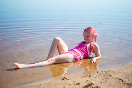 A girl with pink hair is relaxing on a lake on a hot summer day.の写真素材