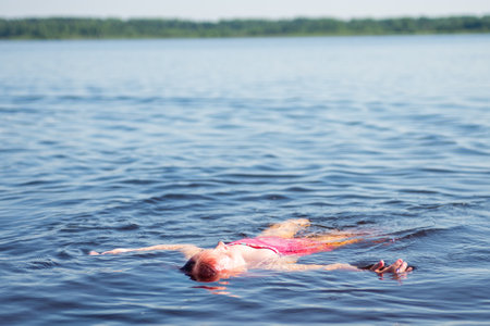 A girl with pink hair is relaxing on a lake on a hot summer day.