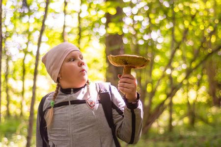 In autumn, a girl collects mushrooms in the forest.