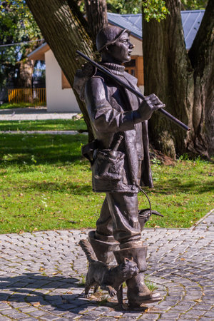 Ostashkov, Tver region, Russia - 08/15/2023. Monument to the fisherman in Ostashkov. A bronze figure of a fisherman with a fishing rod, a bucket of fish and a cat, installed in theの写真素材