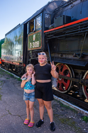 Ostashkov Tver region, Russia-08/25/2024. The girls are standing near the retro train at the Ostashkov railway station.の写真素材