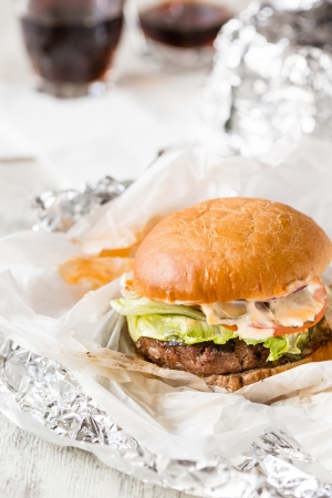 Fresh burger on table just opened with cola on backgroundの写真素材