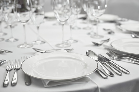 restaurant table setout with white plates and silverwareの写真素材