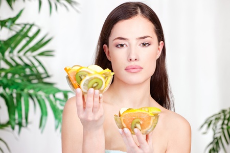 brunette woman holding bowls full of fruitの写真素材