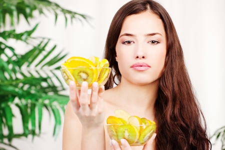 Woman holding two bowl full of fruit in front of palm treeの写真素材