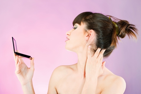 Pretty woman checking face skin, looking at mirrorの写真素材