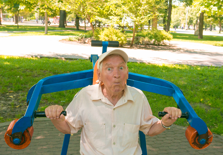 The surprised old man going in for sports on a street simulator in park