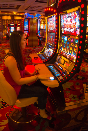 LAS VEGAS - MAY 06, 2016: Concentrated girl playing slot machines in the Excalibur Hotel and Casinoのeditorial素材