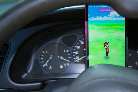 Dnipro, Ukraine - July 23, 2016: An Android user plays Pokemon Go in a car, a free-to-play augmented reality mobile game developed by Niantic for iOS and Android devices.のeditorial素材