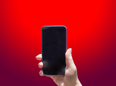The phone in female hand on the red backgroundの写真素材