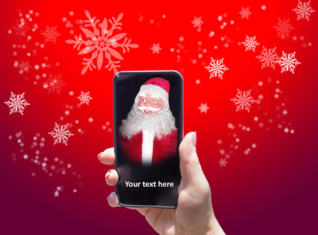 The Santa Claus in female hand with smart phone on red background