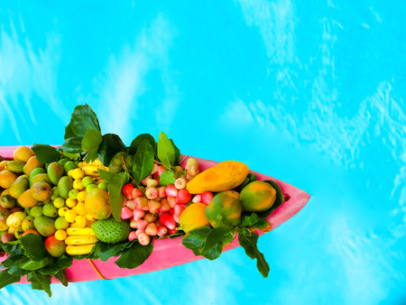 The exotic tropical fruits on the boat canoe against blue water