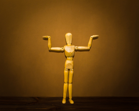 The wooden man with hands up to hold up your banner on brown backgroundの写真素材